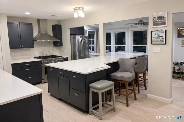 a kitchen with stainless steel appliances kitchen island granite countertop a table chairs and a refrigerator