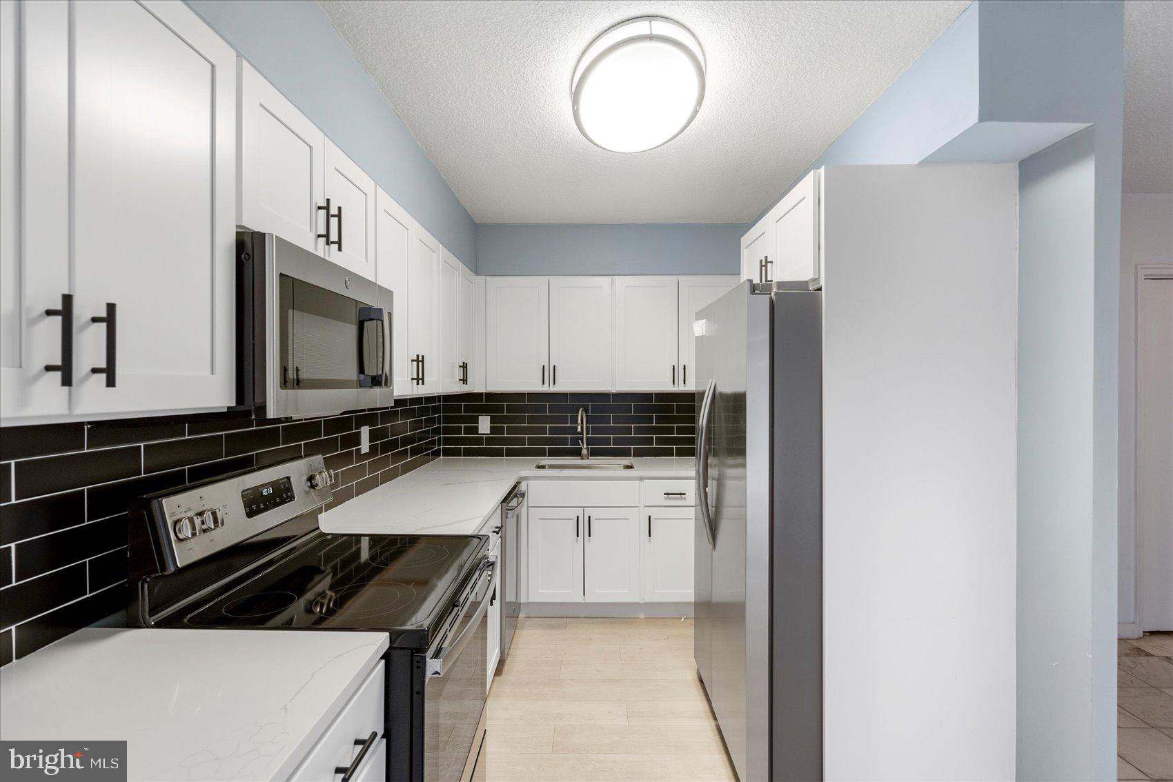 7111 Park Heights Avenue, Unit 305 Baltimore, MD 21215 - Photo 13 of 33 a kitchen with a sink cabinets and stainless steel appliances