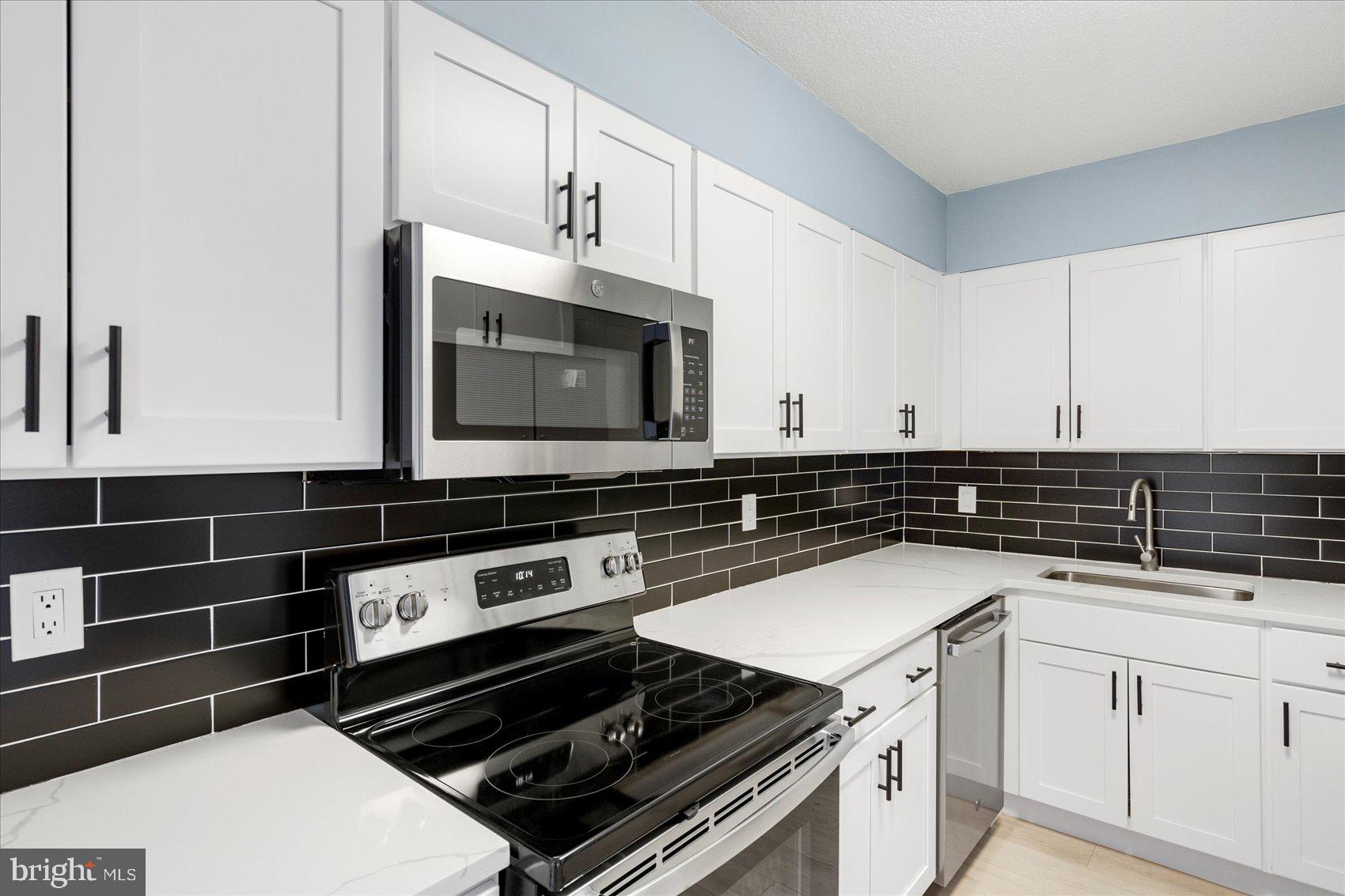 7111 Park Heights Avenue, Unit 305 Baltimore, MD 21215 - Photo 3 of 33 a kitchen with granite countertop a stove and a microwave
