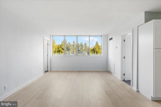 an empty room with wooden floor and window
