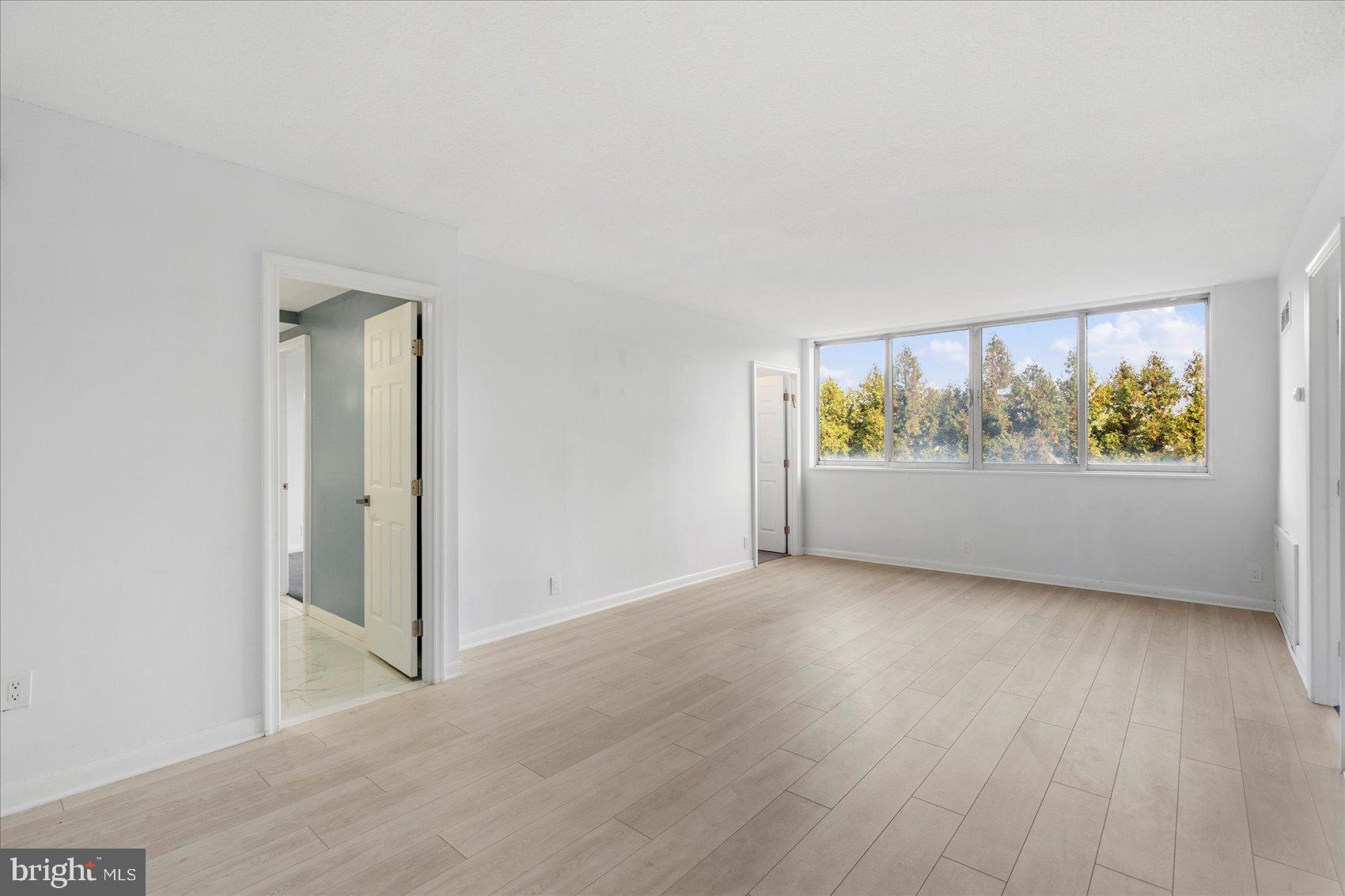 7111 Park Heights Avenue, Unit 305 Baltimore, MD 21215 - Photo 8 of 33 an empty room with wooden floor and window
