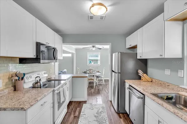 a kitchen with granite countertop a sink stove and refrigerator