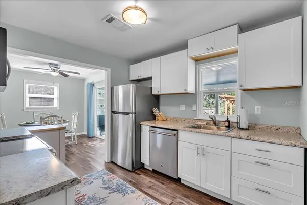 a kitchen with stainless steel appliances granite countertop a sink stove refrigerator and cabinets