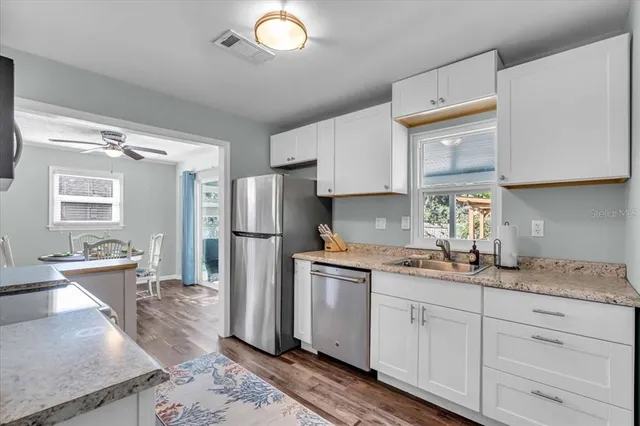 a kitchen with stainless steel appliances granite countertop a sink stove refrigerator and cabinets