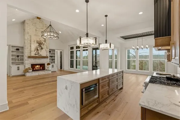 a view of a livingroom with a fireplace a chandelier and wooden floor