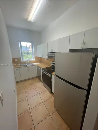 a kitchen with stainless steel appliances a refrigerator sink and white cabinets