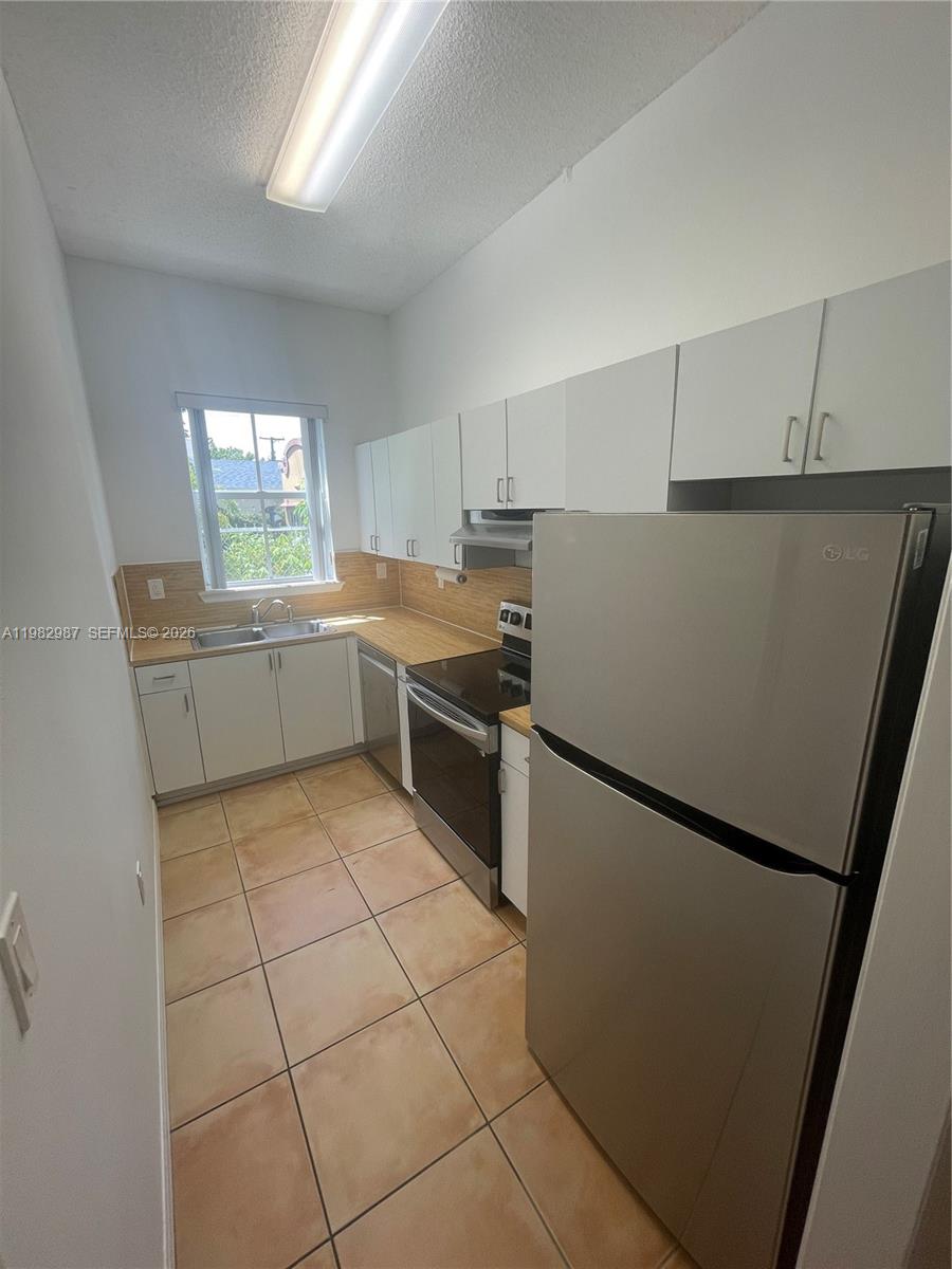 3421 Southwest 25th Street, Unit 1 Miami, FL 33133 - Photo 14 of 41 a kitchen with stainless steel appliances a refrigerator sink and white cabinets