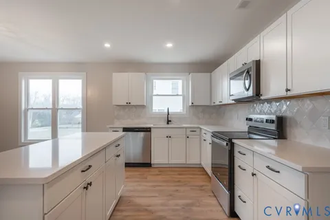 a large kitchen with stainless steel appliances granite countertop a stove a sink and a microwave