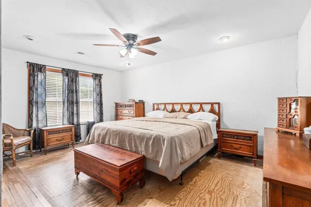 a spacious bedroom with a bed and wooden floor