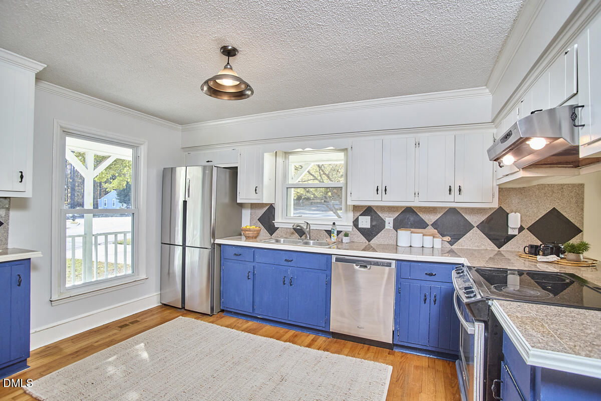 1918 Peppertree Street Durham, NC 27705 - Photo 18 of 45 a kitchen with stainless steel appliances granite countertop a stove a sink dishwasher and a refrigerator with wooden floor