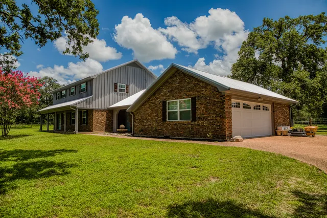 a front view of house with yard and trees in the background