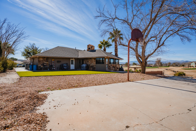 980 Cactus Circle St. George, UT 84790 - Photo 64 of 77 Rear view of house with a chimney, a shingled roof, a lawn, and a patio