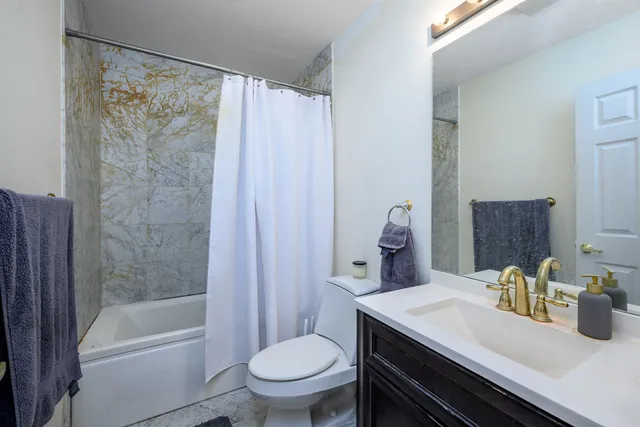 a bathroom with a granite countertop sink a toilet a mirror and shower