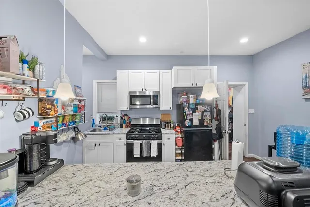 a kitchen with stainless steel appliances kitchen island granite countertop a refrigerator stove top oven and sink