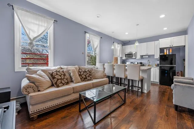 a living room with stainless steel appliances kitchen island granite countertop furniture and a wooden floor