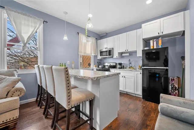 a kitchen with stainless steel appliances granite countertop a refrigerator a stove a sink dishwasher and a dining table with wooden floor