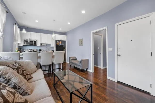 a living room with stainless steel appliances furniture and wooden floor