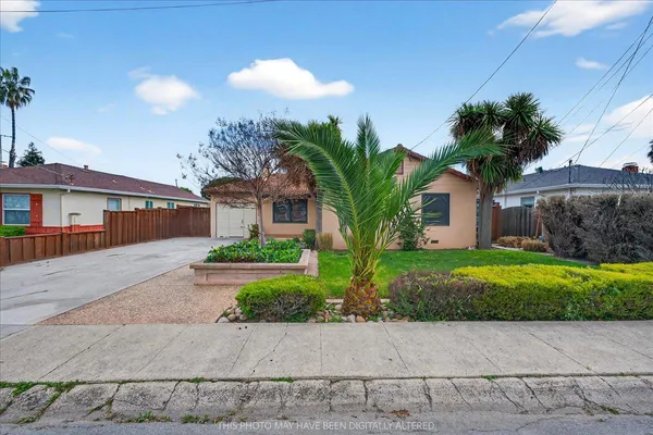 a front view of a house with a yard and potted plants