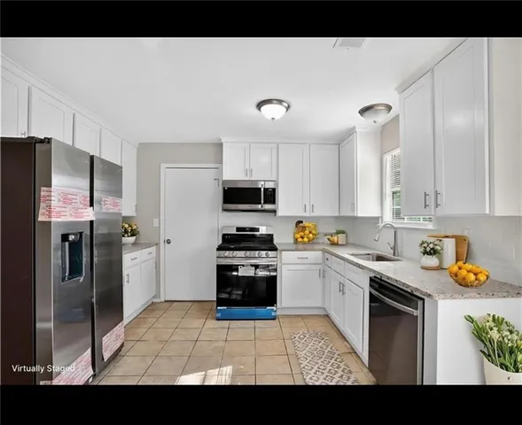 a kitchen with stainless steel appliances granite countertop a refrigerator sink and white cabinets