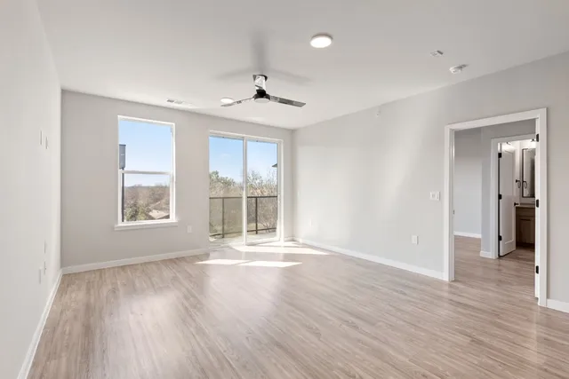 a view of an empty room with wooden floor and a window