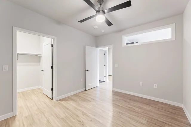 an empty room with wooden floor and ceiling fan