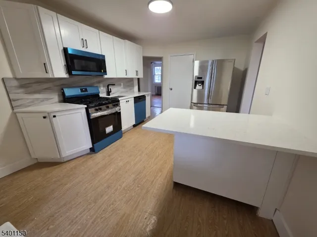 a kitchen with granite countertop a refrigerator and a stove top oven