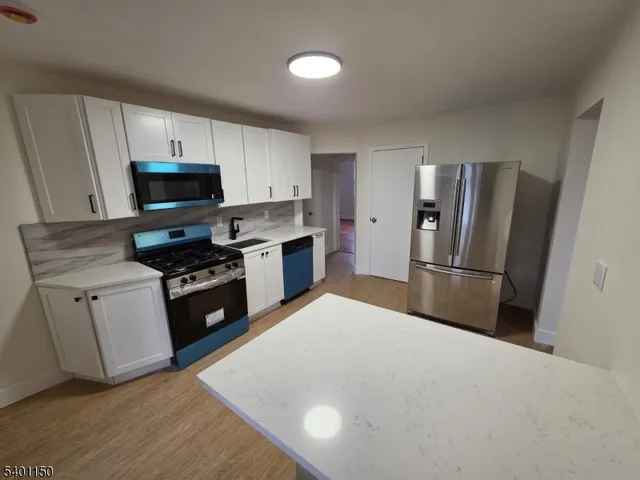a kitchen with granite countertop a refrigerator stove and sink