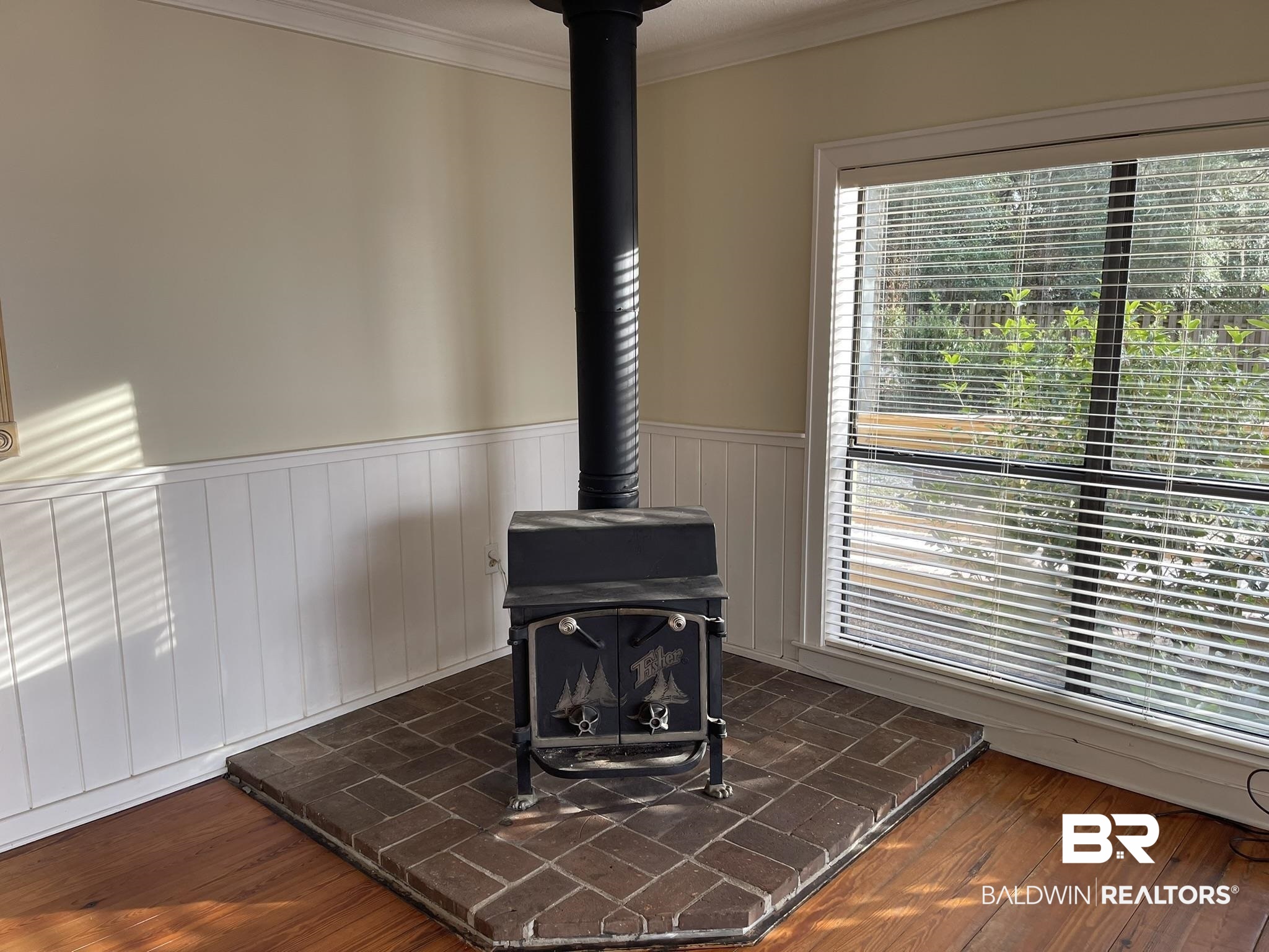 6621 Purvis Road Daphne, AL 36527 - Photo 44 of 59 Detailed view of crown molding, a wood stove, wood finished floors, and a wainscoted wall
