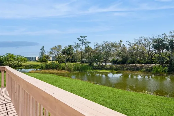 a view of a lake with a yard and large trees