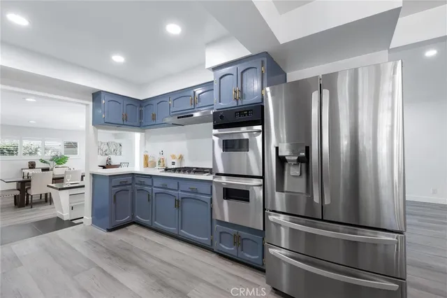 a kitchen with stainless steel appliances kitchen island granite countertop a refrigerator and a sink
