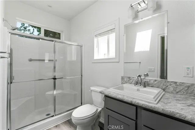 a bathroom with a granite countertop sink a toilet and shower