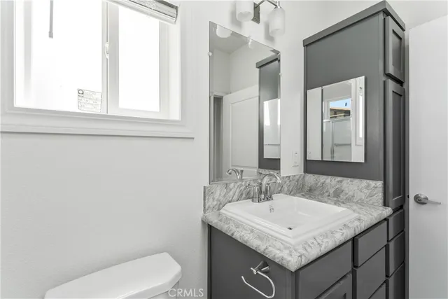a bathroom with a granite countertop toilet sink and mirror