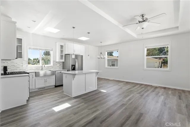 a kitchen with white cabinets a sink dishwasher and a stove with wooden floor
