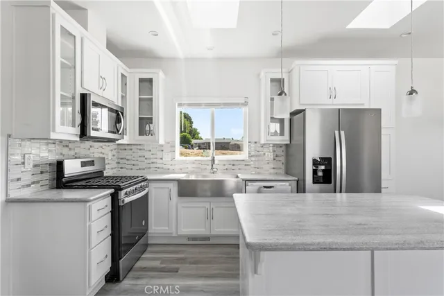 a kitchen with stainless steel appliances granite countertop a sink stove microwave and refrigerator