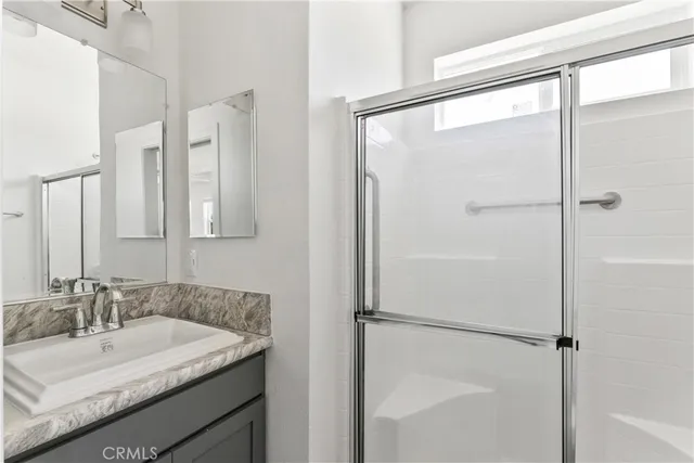 a bathroom with a granite countertop sink mirror and a shower