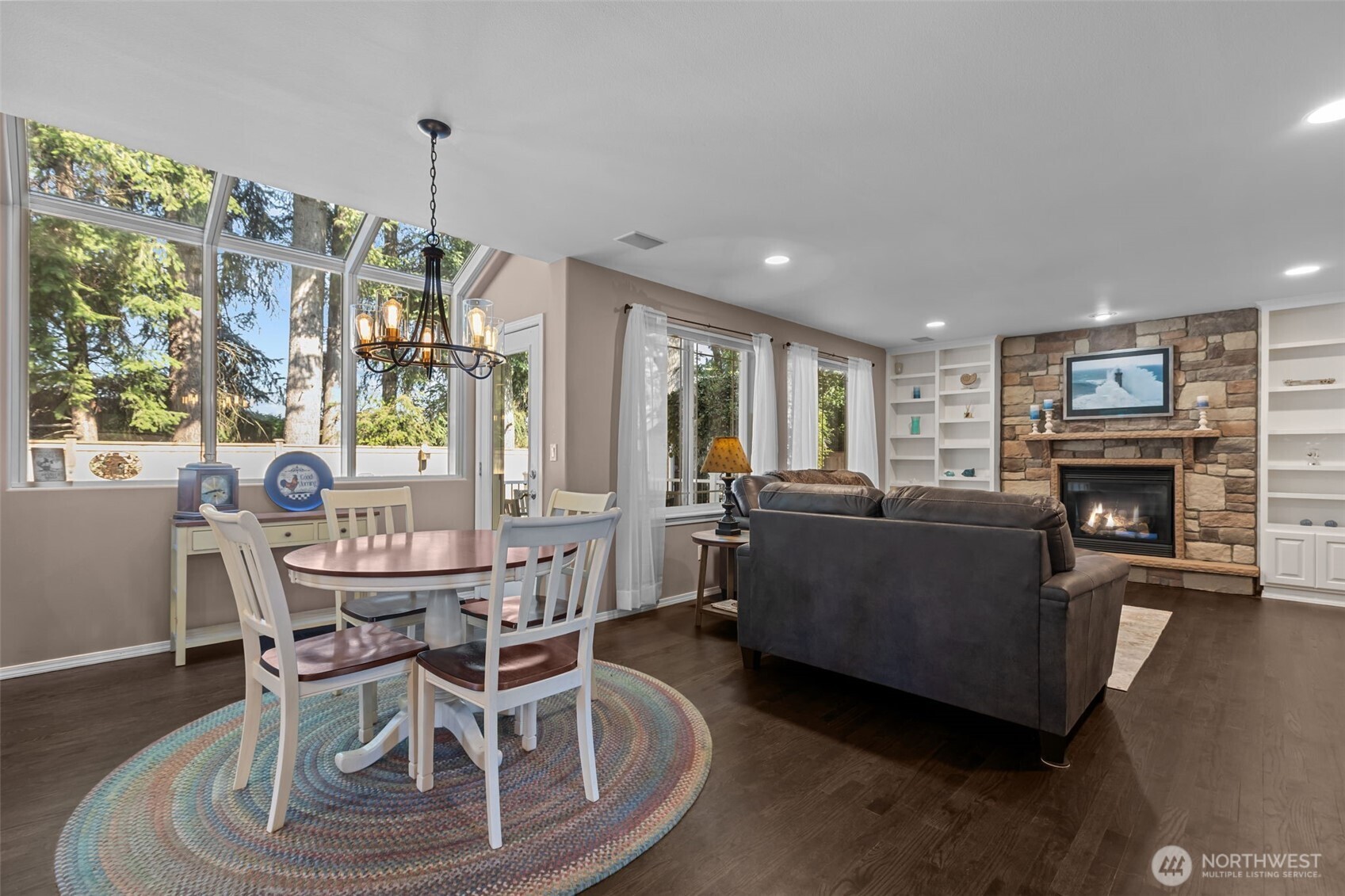 102 Stone Ridge Drive Snohomish, WA 98290 - Photo 17 of 38 a living room with furniture a fireplace and a dining table with wooden floor
