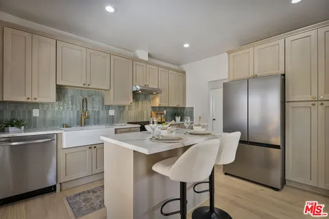 a kitchen with a sink a refrigerator and white cabinets