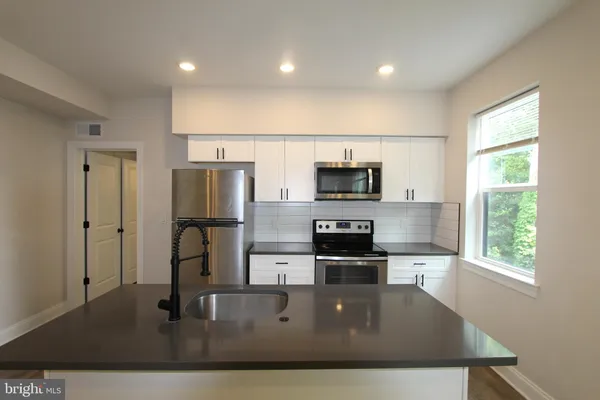 a kitchen with stainless steel appliances a refrigerator a stove a microwave a sink and white cabinets