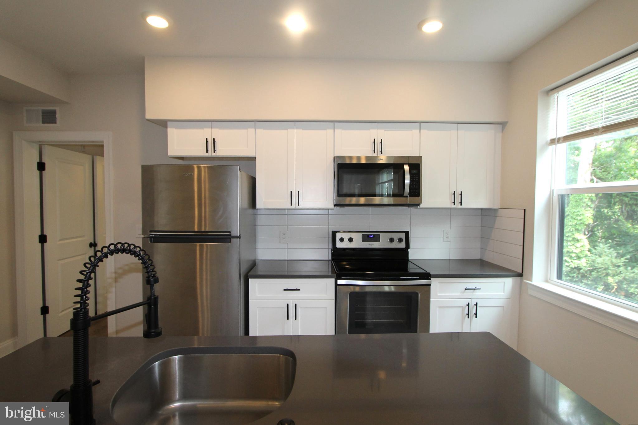 492 Roxborough Avenue, Unit 403 Philadelphia, PA 19128 - Photo 13 of 28 a kitchen with stainless steel appliances a refrigerator sink and microwave
