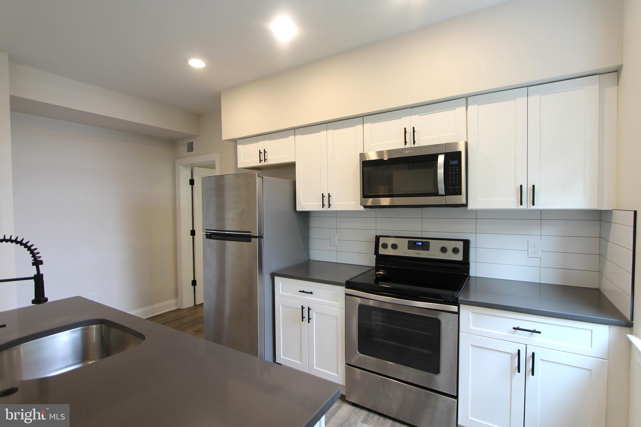 492 Roxborough Avenue, Unit 403 Philadelphia, PA 19128 - Photo 14 of 28 a kitchen with a sink stove and microwave