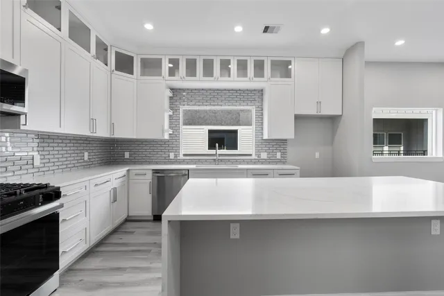a kitchen with kitchen island granite countertop a stove top oven a sink dishwasher and white cabinets