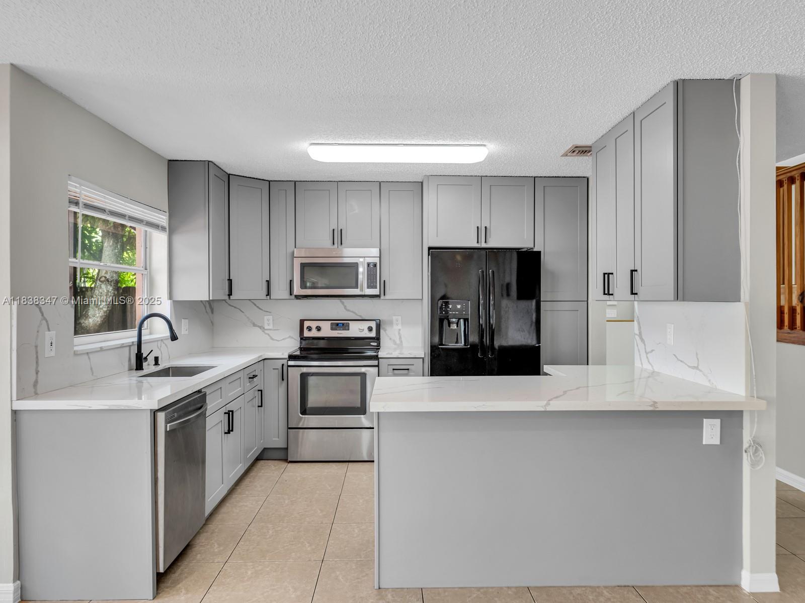 18232 Southwest 5th Street Pembroke Pines, FL 33029 - Photo 12 of 53 a kitchen with stainless steel appliances a refrigerator sink and white cabinets