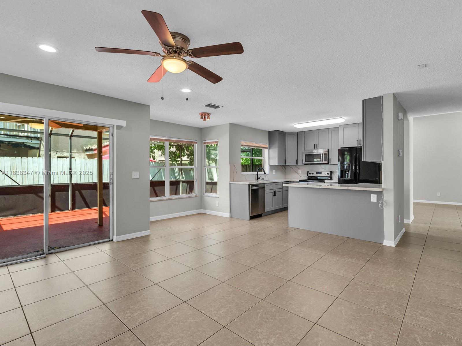 18232 Southwest 5th Street Pembroke Pines, FL 33029 - Photo 10 of 53 a large white kitchen with a stove a sink dishwasher and a refrigerator with a dining table