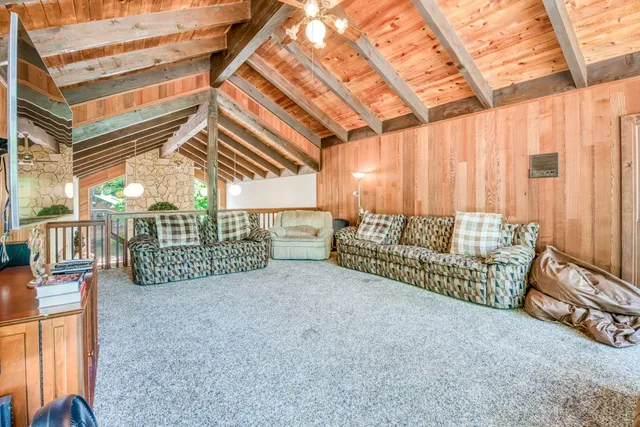 a spacious bedroom with a bed a couch and a chandelier fan