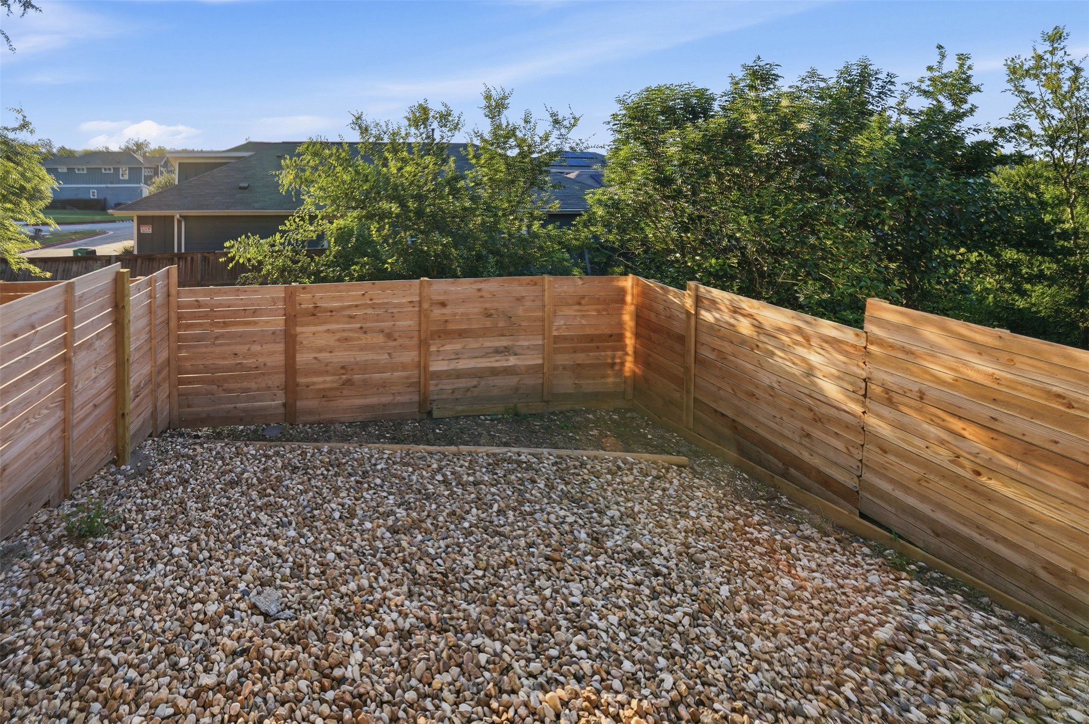 2212 Yellow Jacket Lane, Unit 2 Austin, TX 78741 - Photo 24 of 25 Private outdoor area featuring new horizontal plank fencing, a gravel surface, and mature perimeter trees