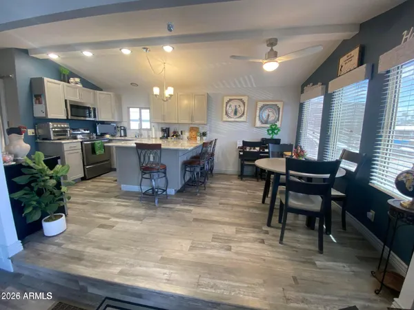 a living room with furniture a dining table and kitchen view with wooden floor