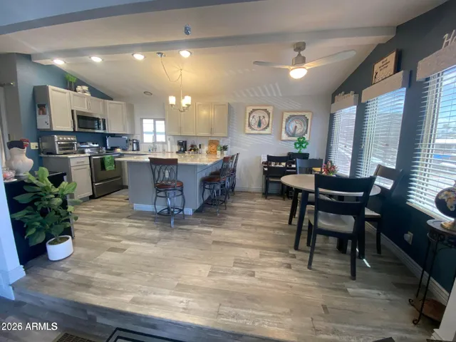 a living room with furniture a dining table and kitchen view with wooden floor