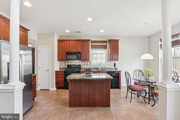 a large kitchen with stainless steel appliances granite countertop a stove a sink dishwasher a oven and a dining table with the living room