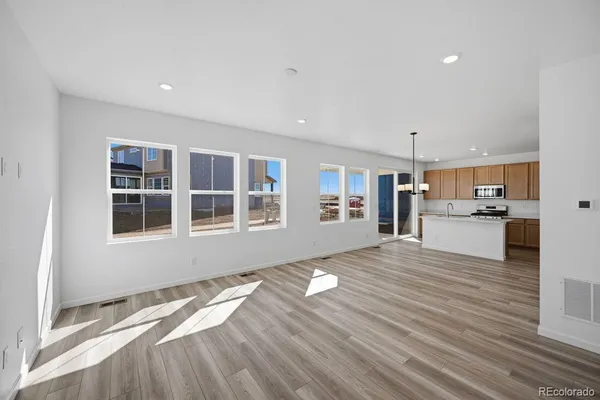 a view of an empty room with kitchen and window