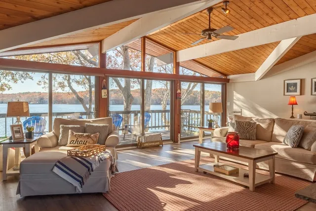 a living room with furniture and a floor to ceiling window next to a yard